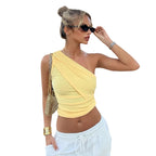 Woman wearing a yellow one-shoulder top and white pants on a white background