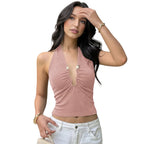 Woman wearing a pink halter top and white pants in a garden setting