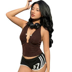 Woman in a brown top and black shorts with white stripes on a city street.